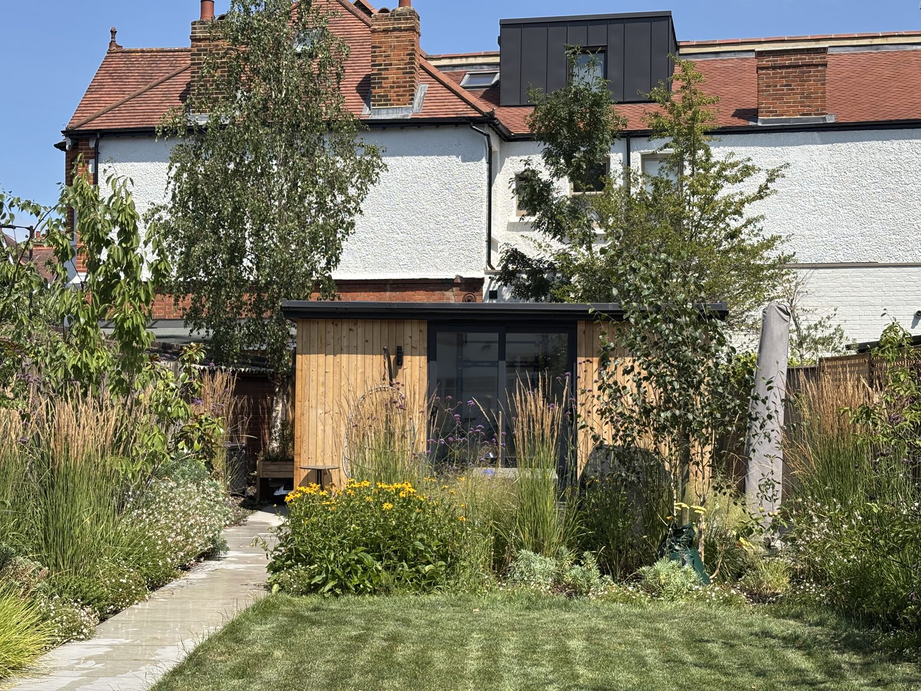 Dulwich Village garden with striped lawn, naturalistic planting and timber studio